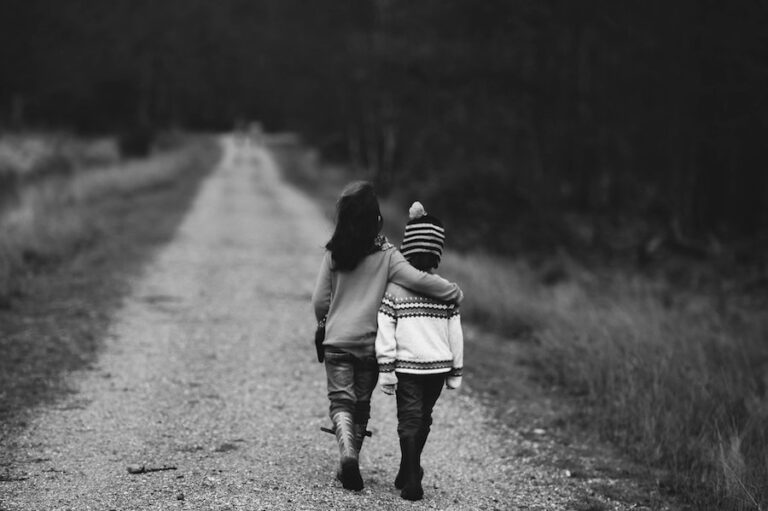 to barn går på en landevei arm i arm. Med ryggen til, bildet i sort hvitt.