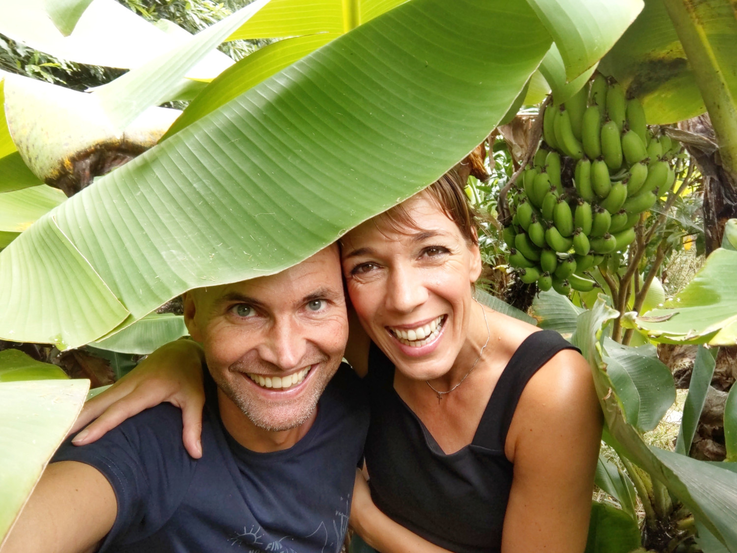 mann og kvinne smiler og holder armene rundt hverandre, et grønt blad i forgrunnen