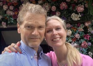 mann og kvinne med hodene tett ved hverandre, begge lyse, smiler mot kamera